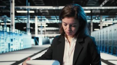 Altyapı durumu, dosya dosyaları ve holografik görsellerle veri merkezinde yönetici doğrulaması yapılıyor. Denetleme ekipmanları, kablo simülasyonu ve denetim çizelgeleri, kamera A kullanarak sunucu odasında çalışan.