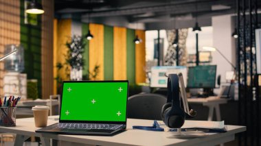 Kurumsal iş ortamında dizüstü bilgisayarı olan boş yönetici masasında krom anahtar ekranı. Modern mobilyaların, dekoratif detayların ve ofis malzemelerinin olduğu geniş pencereli doğal ışık..