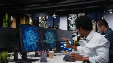 Yüksek katlı ofiste gece vardiyası sırasında yapay zeka algoritmaları geliştiren bir teknoloji firması. Afrikalı Amerikalı adam ekranlarda sinir ağı beyin modellerini hata ayıklıyor