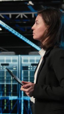 Yükseltilmiş gerçeklik kontrol paneli kullanarak kule yapılandırması yapan dikey video veri merkezi mühendisi. Sunucu çiftliğinde yürüyen kadın, donanım ayarlarını ayarlamak için sanal holografik görselleştirmeyle etkileşime geçiyor