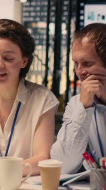 Şirket ofis ortamında dizüstü bilgisayarlı ve masada raporlu dikey video ekibi işbirliği. KPI 'yi inceleyen profesyoneller, planlama ve karar verme sürecini desteklemek için gelir verileri ve grafikler.