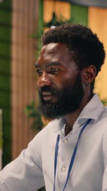 Dikey Video Siyah erkek profesyonel modern ofiste görev yönetimi yapıyor, kontrol panelleri ve dizüstü bilgisayardaki KPI görsel verilerini analiz ediyor. İstihbarat ve parasal görüşe sahip küresel iş amaçları.