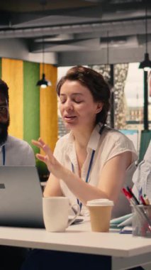 Şirket ofis ortamında dizüstü bilgisayarlı ve masada raporlu dikey video ekibi işbirliği. KPI 'yi inceleyen profesyoneller, planlama ve karar verme sürecini desteklemek için gelir verileri ve grafikler.