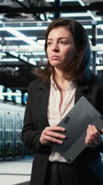 Dikey video veri merkezi kadın programcısı sunucu yükü dengeleme ve VFX bileşimini optimize etmek için dijital ikiz taraması yapıyor. Sistem parametrelerini ayarlamak için AR simülasyonu ve aygıtı kullanan sunucu merkezi çalışanı