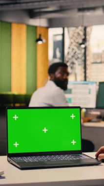 Ofis masasında çalışan bir kadınla birlikte dizüstü bilgisayarda dikey video yeşil ekran modeli, küresel iş analizleri ve tahmin raporlarını inceleyen profesyonel bir çalışan. Geliştirme için iş zekası.