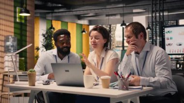 Kurumsal ofis ortamında dizüstü bilgisayar ve raporlarla takım çalışması. KPI 'yi inceleyen profesyoneller, planlama ve karar verme sürecini desteklemek için gelir verileri ve grafikler.