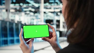Sunucu merkezi çalışanının video izlerken kullandığı yeşil ekran akıllı telefon. Veri merkezindeki yazılım geliştirici elinde kroma anahtar cep telefonu olan, online kliplere bakan, kamera A