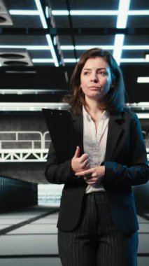 Dikey video denetleme donanımı, mavi kablo örgüleri ve veri merkezinde yönetici. AR veri akışlarına, dijital ikiz simülasyonuna ve sunucu merkezinde yürüyen sistem yöneticisine bakıyorum.