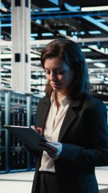 Tablet üzerinde dikey video veri merkezi yazılım geliştirici kodlaması, artırılmış gerçeklik dijital ikizi yaratmak için sondaj platformlarını tarıyor. Sunucu çiftliğindeki kadın aygıt üzerinde programlama betiği çalıştırıyor, VFX üstüste, kamera A