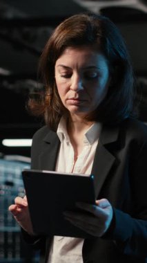 Veri merkezinde yürüyen dikey video mühendisi tablet kullanarak endüstriyel otomasyon sistemlerini izliyor. Ağ ekipmanı performansını denetlemek için aygıt kullanan sunucu odası bilişim uzmanı, kamera B