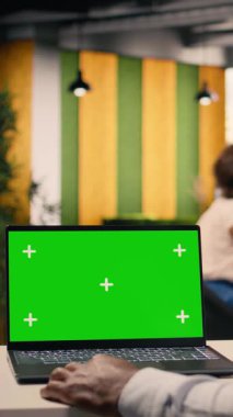 Dikey video yeşil ekran dizüstü bilgisayar, siyah iş adamı, modern bir ofiste, görsel verileri, grafikleri ve grafikleri gözden geçirir. Performans ölçümleri, KPI gösterge paneli, tahmin raporları, kurumsal strateji, küresel