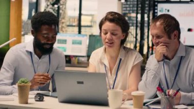 Kurumsal ofis ortamında dizüstü bilgisayar ve raporlarla takım çalışması. KPI 'yi inceleyen profesyoneller, planlama ve karar verme sürecini desteklemek için gelir verileri ve grafikler.