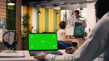 Yeşil ekran laptop, siyah iş adamı, modern bir ofiste, görsel verileri, grafikleri ve grafikleri gözden geçirin. Performans ölçümleri, KPI gösterge paneli, tahmin raporları, şirket stratejisi, küresel işletme.