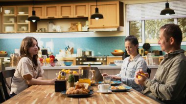 Annem dizüstü bilgisayarla uzaktan kontrol ederken, ergen kız, babası, ailesi ve kızıyla mutfakta ev yapımı yemek yerken sohbet ediyor. Hafta sonları bağ kurma zamanı.