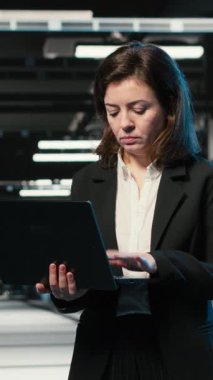 Dikey video veri merkezindeki kadın teknisyen yapay zekanın platformları optimize etmesi için çabalıyor. Sunucu merkezi çalışanı, yapay zeka öğrenme hatası yüzünden kaşlarını çatmış.