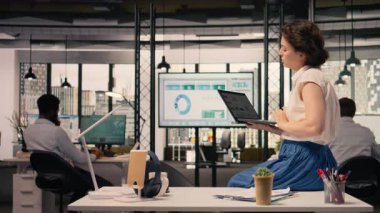 Çizelgelere, analitik gösterge paneline, modern şirket ofisine odaklanmış bir kadın işçi. İş zekası, performans ölçümleri, organizasyonel geliştirme, üretkenlik araçları.