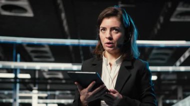 Teknoloji sorunları teşhis ediliyor, AR holografik bilişim destek çalışanı veri merkezinde. Kulaklık mikrofonuyla konuşmak, artırılmış gerçeklik simülasyonu ve şebeke sorunlarını belirleyen kadın, kamera B