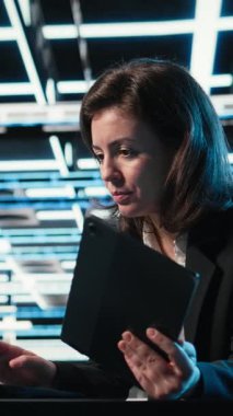 Dikey Veri Merkezi yazılım geliştiricisi dijital ikiz simülasyonu için aygıtları kontrol paneli olarak kullanır. Mavi kablo ağ donanımını ayarlamak için dizüstü bilgisayar ve tablet kullanan sunucu merkezi kadın programcısı