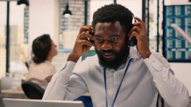 Modern ofiste müzik kulaklığı takan siyahi bir çalışan, çalışma alanı neşeli ve keyifli. Stres atmak için şarkı dinleyen bir adam. Dengeli kurumsal yaşam tarzı.