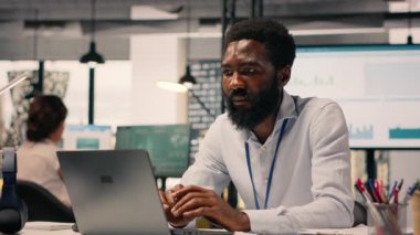 Organizasyon başarısı için dizüstü bilgisayardaki görevleri çözen siyah çalışanların portresi, KPI ve parasal verilerle performans değerlendirmesi yapmak. Ofiste verimlilik ve kurumsal yaşam tarzı.