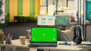 Yeşil ekran laptop çalışma istasyonunda boş, açık ofis, mobilya ve ofis malzemeleriyle modern şirket alanı. Doğal ışık ile rahat çalışma ortamı.