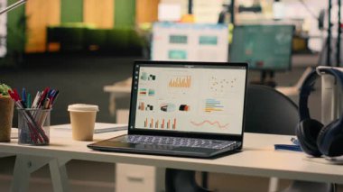 Şirket veri raporları boş bir iş ofisinde dizüstü bilgisayarda çalışıyor, veri analizi ve performans ölçümlerini masa kurulumunda gösteriyor. Doğal ışık ile modern parlak çalışma ortamı.