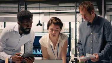 Şirket ofisinde işbirliği yapan iş ekibi raporlardaki görsel verileri, çizelgeleri ve grafikleri kontrol ediyor. Profesyoneller brifing sırasında performans ölçümleri ve eylem planını tartışırlar. Kamera B.