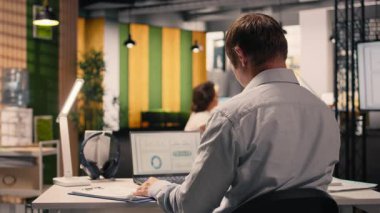 Masadaki dizüstü bilgisayardaki uyum verilerini inceleyen, performans değerlendirmesi yapan ve ofiste risk değerlendirmesi yapan profesyonel bir işçi. İş istihbaratı verimliliği için görsel veriler.