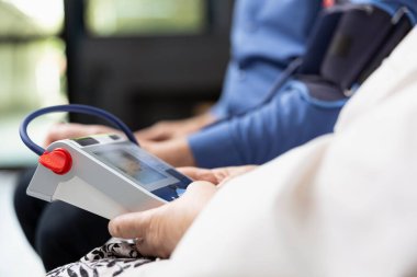 Klinik bekleme odasındaki kan basıncını analiz etmek için sağlık hizmetleri izleme cihazı kullanan tıbbi personeli kapatın. Doktor muayeneden önce rutin tarama testleri yapar..