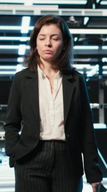 Dikey Veri Merkezi Yöneticisi mavi kablo ağ donanım valflerini inceliyor. Sunucu merkezi satırlarında yürüyen sistem yöneticisi AR dijital ikiz veri akışlarına bakıyor, kamera B