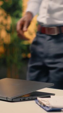 Dikey Video Afrikalı Amerikalı adam, laptop, modern ofis, görsel veri, KPI ölçümleri, iş zekası, geliştirme, performans denetimi, araştırma ve geliştirme için planlama.