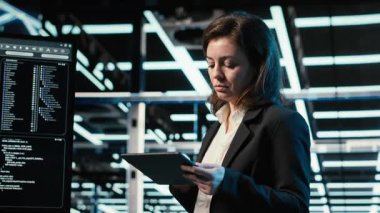 Veri merkezi programcısı tablet üzerinde kodlama yapıyor, dijital ikiz oluşturmak için ekipman donanımı tarıyor. Sunucu merkezindeki kadın teknisyen aygıt, VFX bileşimi, kamera B üzerinde programlama betiği çalıştırıyor