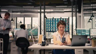 Ofisteki iş yerindeki video görüşmesine katılan gülümseyen kadın, online toplantı için akıllı telefonu kullanıyor. Şirket video konferansı strateji, KPI analizi ve performans değerlendirmesi üzerine odaklandı.