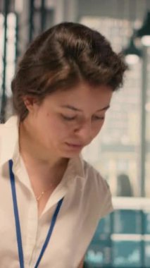 İş zekasını ve analitik gösterge panelini şirket ofisinde inceleyen kadının dikey video portresi. Görsel veriler, performans ölçümleri ve tahmin raporları stratejik