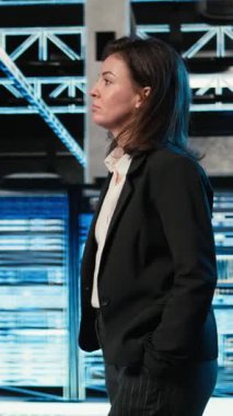 Dikey Veri Merkezi Yöneticisi VFX bileşikli mavi kablo örgülü ekipman donanımlarını inceliyor. Sunucu merkezinde yürüyen bilişim uzmanı, donanımlı artırılmış gerçeklik simülasyonuna bakıyor