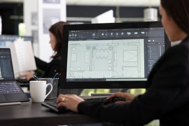 Genç bayan mimar, inşaat süresi dolmadan dijital kat planlarını monitörden inceliyor. Mimari tasarımcı ölçümleri, tasarım ayrıntılarını ve proje yapısını hassasiyetle değerlendirir.