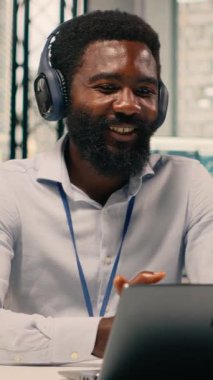 Modern ofisteki kulaklıklarla video konferansına katılan Dikey Siyah profesyonel. Çevrimiçi brifing, şeffaflık ve