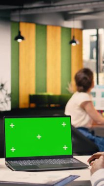 Dikey video mavi ekran ve laptopta siyah adamla birlikte yeşil ekran, veri analizi ve iş istihbaratını gözden geçiriyorlar. Profesyonel ofis faaliyetleri, görsel veriler ve raporlar kaynaklara yardımcı olur