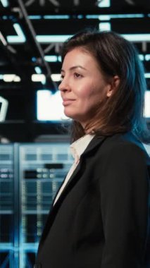 Veri merkezinde yürüyen dikey video mühendisi endüstriyel otomasyon sistemlerine bakıyor. Dijital ikiz sanal. Sunucu odası bilişim uzmanı mavi kablo ağ ekipmanı tarıyor, kamera A