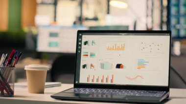 Boş iş ofisindeki dizüstü bilgisayarda çalışan raporlar, veri analizleri ve masa kurulumunda performans ölçümleri gösteriliyor. Doğal ışık ile modern parlak çalışma ortamı.
