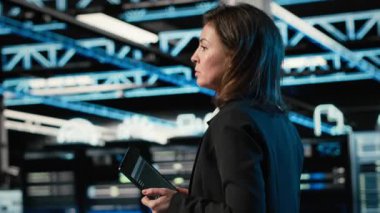 Veri merkezi mühendisi artırılmış gerçeklik kontrol paneli kullanarak sondaj kulesini yapılandırıyor. Sunucu çiftliğinde yürüyen kadın, donanım ayarlarını ayarlamak için sanal holografik görselleme ile etkileşim içinde, kamera B