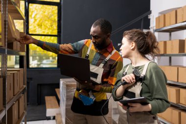 Çok ırklı bir ekip, depolanan malların etiketlerini kontrol etmek için tarayıcı kullanıyor, küçük teslimatlara odaklı bir e-ticaret deposunun perakende envanesini tutuyor. İşlem ve dağıtım sırası.