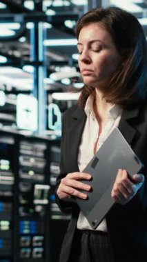 Dikey video veri merkezi kadın programcısı sunucu yükü dengeleme ve VFX bileşimini optimize etmek için dijital ikiz taraması yapıyor. Sistem parametrelerini ayarlamak için AR simülasyonu ve aygıtı kullanan sunucu merkezi çalışanı