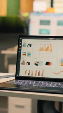 Boş iş ofisindeki dizüstü bilgisayarda çalışan Dikey Video Şirketi veri raporları, masa kurulumunda veri analizi ve performans ölçümleri gösteriliyor. Doğal ışık ile modern parlak çalışma ortamı.