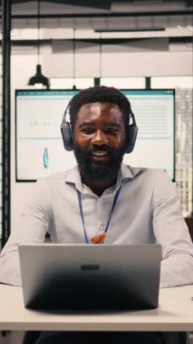 Modern ofisteki kulaklıklarla video konferansına katılan Dikey Siyah profesyonel. Çevrimiçi brifing, şeffaflık ve