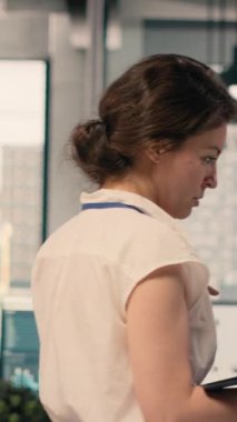 Dikey Videolu Kadın modern ofiste yerde volta atıyor ve sabırsız, huzursuz ve gergin olduğu için ileri geri yürüyor. Odaklanmış ve endişeli kadın işçi, iş zekası..