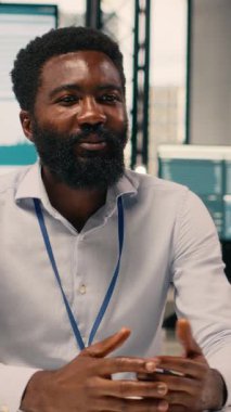 Dikey Video Afrikalı Amerikalı iş adamı, ofisinden yapılan video görüşmesi sırasında iş birliği yapıyor. Çok uluslu şirkette dizüstü bilgisayar destekli tartışma, analiz ve stratejik planlama