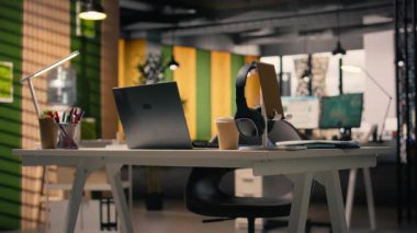 Modern mobilyaları olan boş bir iş yeri, şık dekorasyonları ve masa kurulumunda kırtasiyesi olan parlak bir açık alan. Pencereler üretkenlik için doğal ışık sağlar.