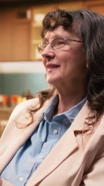 Dikey Videolu Kadın emeklisi bir fincan kahveyle rahatlıyor ve tek başına vakit geçiriyor, koltukta oturuyor ve evdeki huzurlu anları hayal ediyor. Yaşlılıkta sağlık ve sükunet.