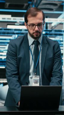 Yükseltilmiş sunucu rafları kurmak için laptop ve artırılmış gerçeklik kullanan dikey video veri merkezi teknisyeni. Sunucu çiftlik performansını, VFX kaplamasını ve kamerayı izlemek için otomasyon araçları kullanan işçiler